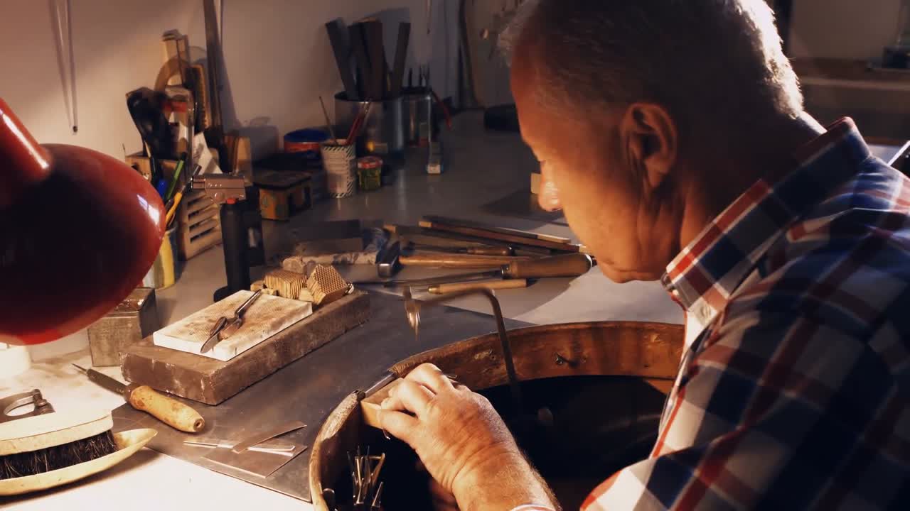 orfebre que da forma al metal con una sierra de copado