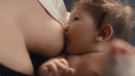 close up of asian baby breastfed by mother and playing with his legs