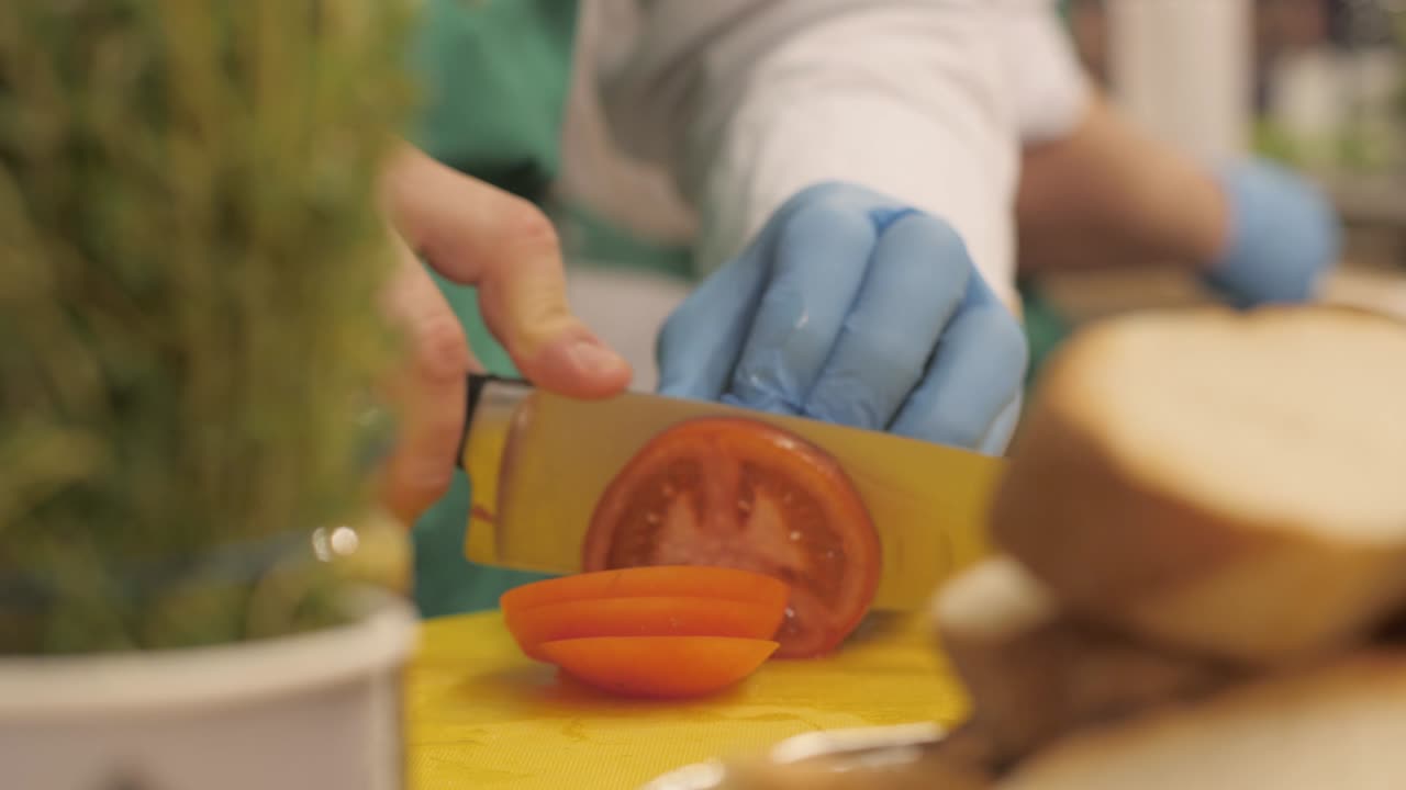 레스토랑에서 토마토를 원형 조각으로 잘라내는 칼을 사용하는 요리사의 손