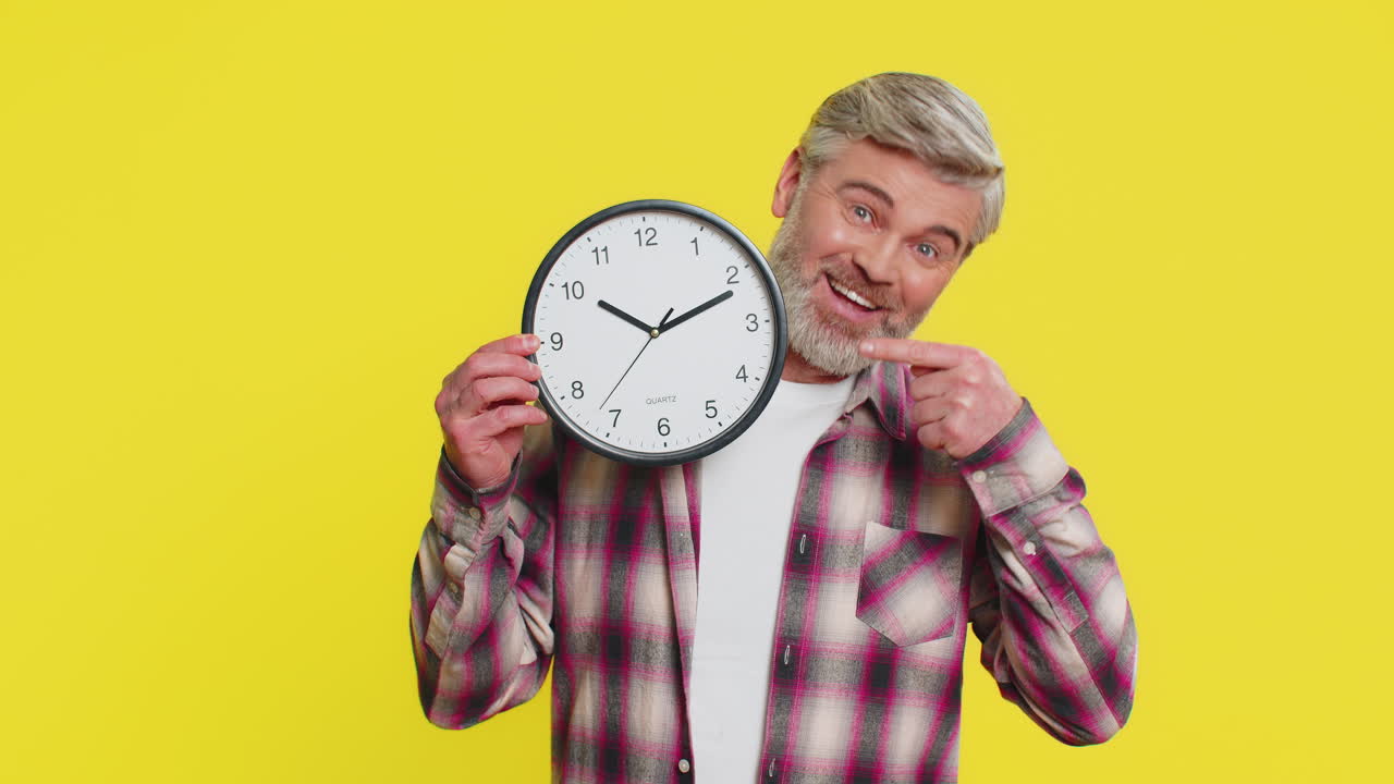 Mature man hiding behind large office clock playful peek cautious glance time awareness humor