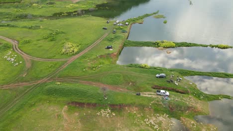 Umgekehrte-Luftaufnahmen-Von-Fahrzeugen,-Die-Am-Rand-Des-Sees-Geparkt-Sind,-Während-Menschen-Picknicken-Und-Angeln,-Reflexion-Von-Wolken-Auf-Dem-See,-Muak-Klek,-Saraburi,-Thailand