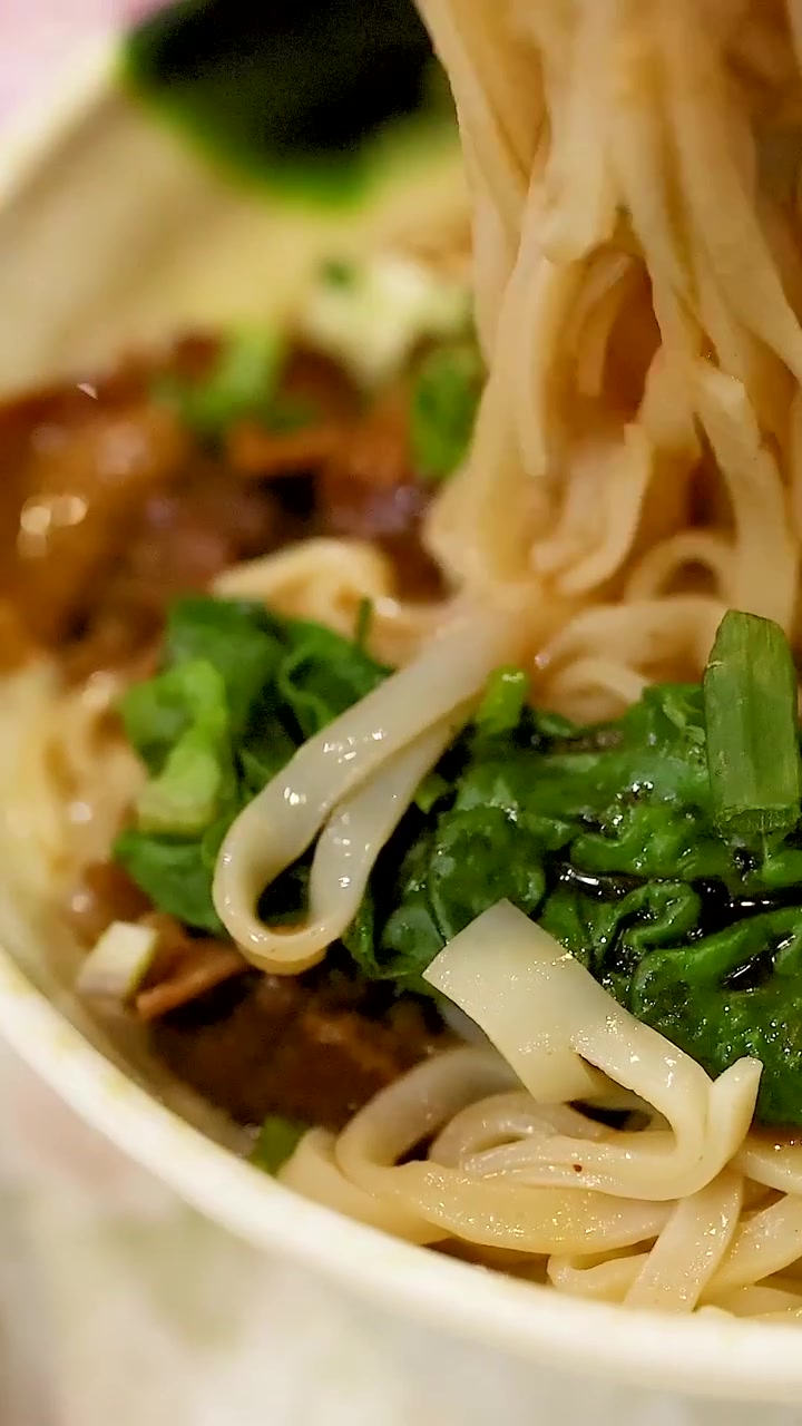 Bacchette che sollevano noodles da un piatto saporito
