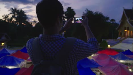 tourist taking a photo of a night market scene