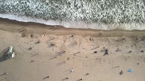 Una-Toma-Cinematográfica-Aérea-De-Un-Dron-De-La-Playa-De-Santa-Mónica,-En-La-Que-Aparecen-Personas-No-Identificadas-Y-Olas-Rompiendo-A-Lo-Largo-De-La-Costa.