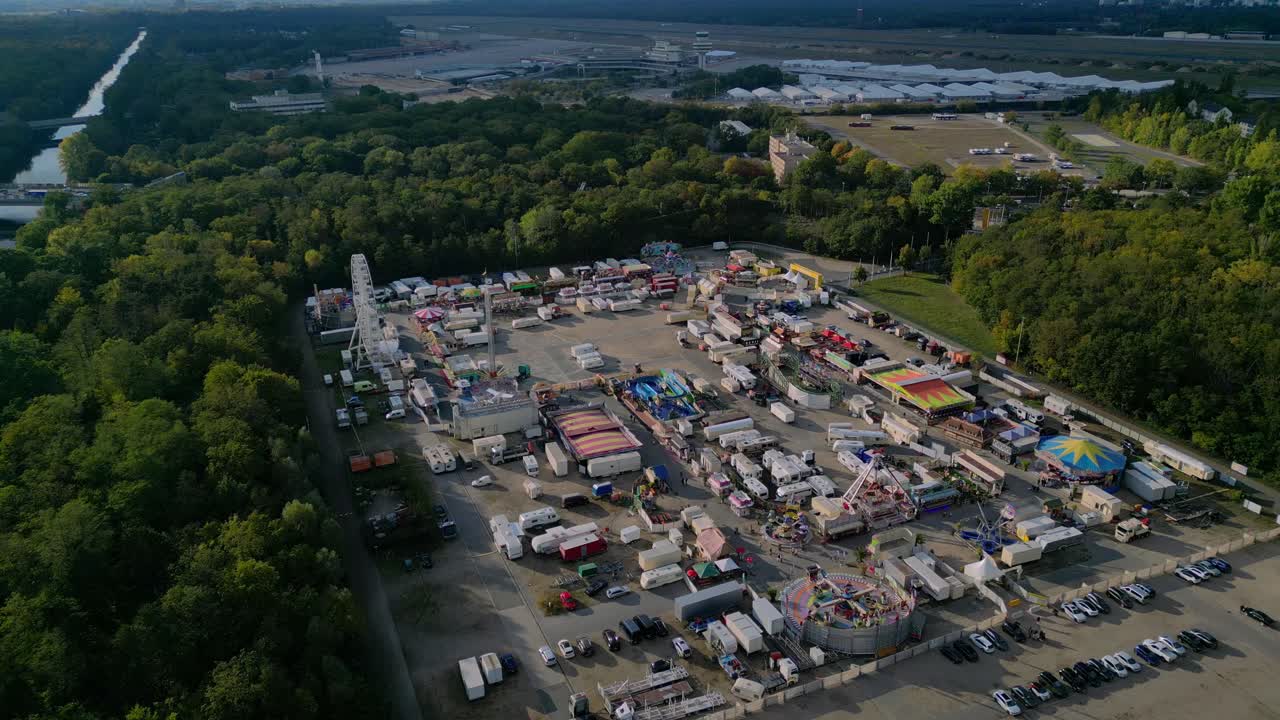 outdoor forest fairground, funfair, carnival with rides and stalls surrounded by forest. Unique aerial view flight drone camera pointing down