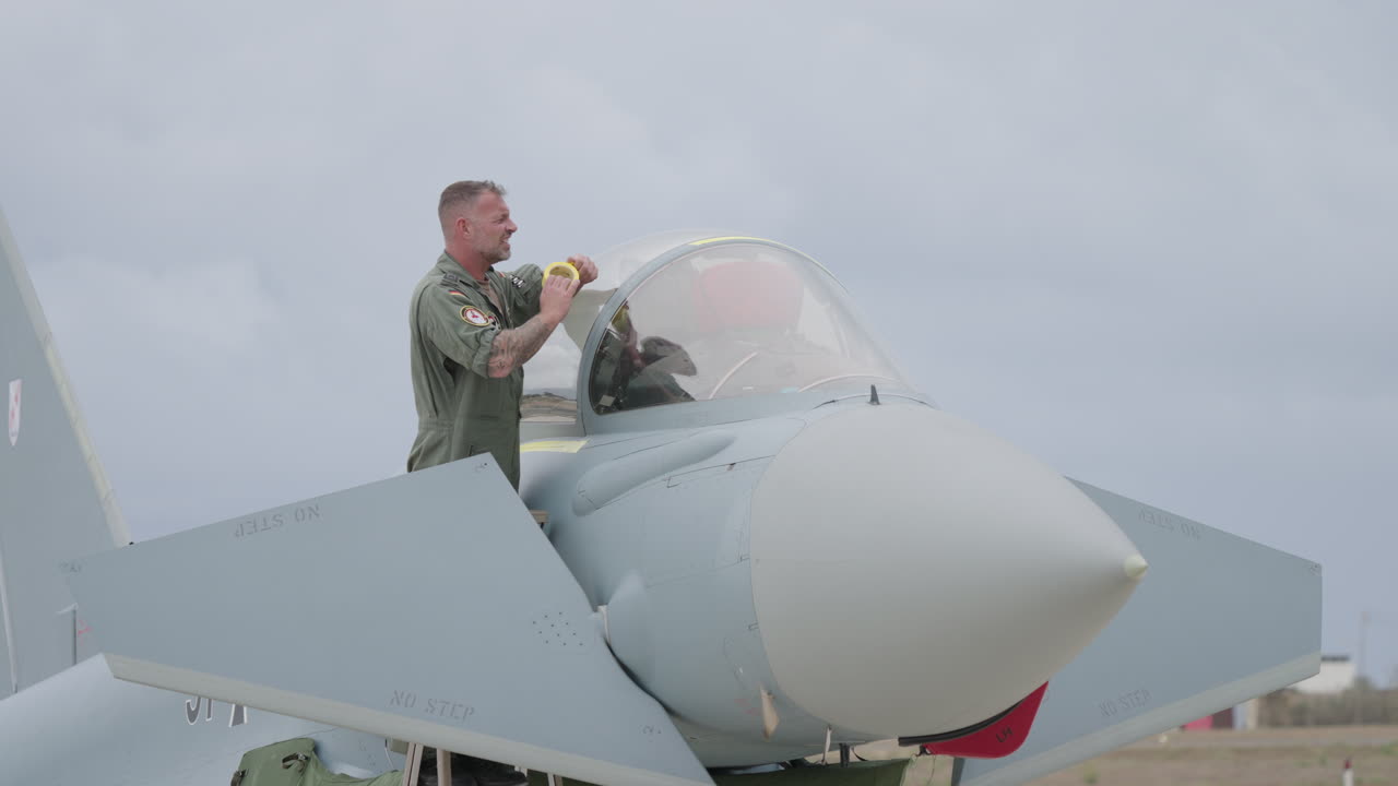 Military Pilot Inspects Cockpit Canopy of Fighter Jet on Airfield