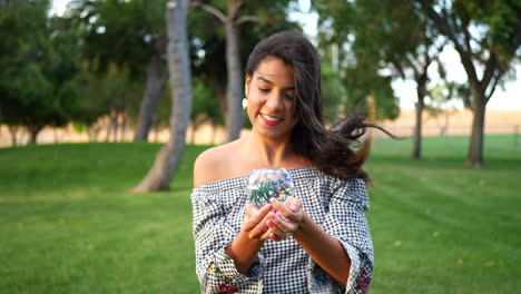 una linda mujer hispana sonriendo alegremente y caminando en un parque con una bola de cristal mágica