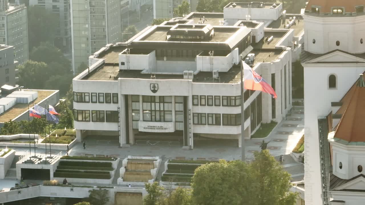 Aerial shot of the Slovak National Council building in Bratislava, featuring the modern architecture and surrounding cityscape. Captures the essence of Slovakia's political hub from above. (4K)