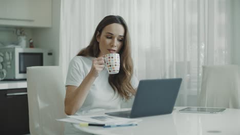 Mujer-Usando-Computadora-Portátil-En-La-Cocina.-Retrato-De-Mujer-De-Negocios-Viendo-Noticias