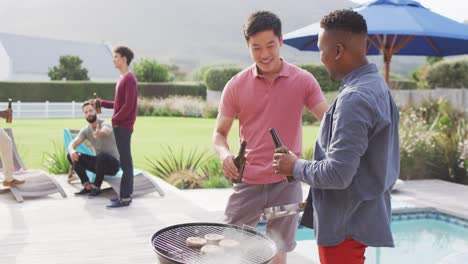 Happy-diverse-male-friends-talking-and-drinking-beer-in-garden-on-sunny-day