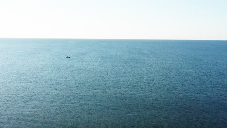 Cielo-Azul-Y-Mar-Con-Un-Pequeño-Barco-Bajo-El-Sol.-Toma-Aérea-De-La-Costa-Mediterránea.