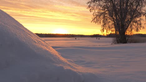 Tiro-De-Seguimiento-De-Personas-Pescando-En-El-Hielo,-En-El-Mar-Cubierto-De-Nieve,-Al-Atardecer,-En-Una-Soleada-Tarde-De-Invierno,-En-Ostrobotnia,-Finlandia