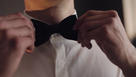 groom adjusts bow tie, preparing to go to the bride, businessman in white shirt, wedding day