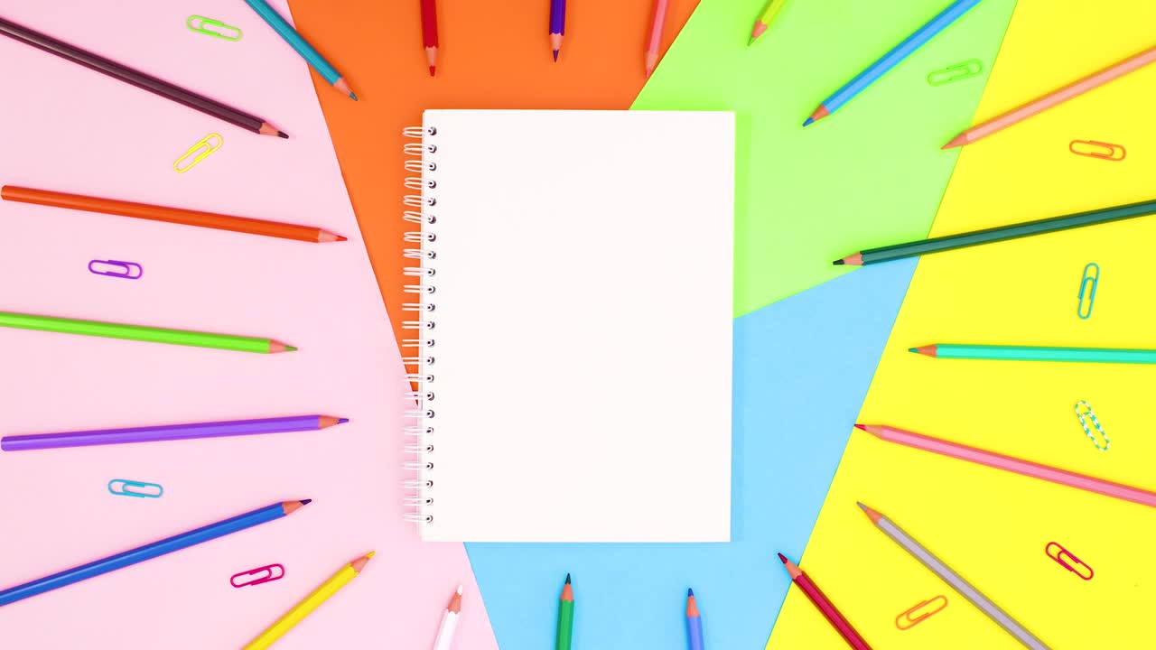 abre el cuaderno y los lápices y los clips de papel aparecen en el tema colorido.