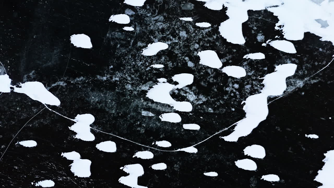Frozen fjord ice with cracks and snow patches, abstract patterns in Arctic nature
