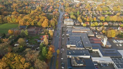 Aerial-of-long-road-running-through-a-beautiful-town-in-autumn