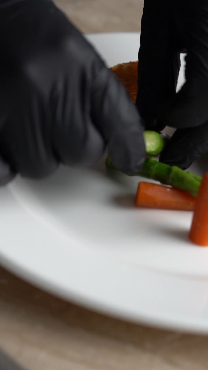 Impiattamento di un pezzo di pollo arrosto con carote e fagiolini su un piatto, inquadratura ravvicinata.