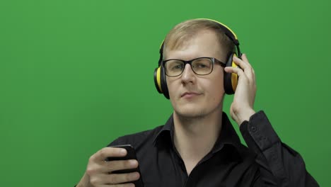 guy listens to music in wireless yellow headphones and dances. chroma key