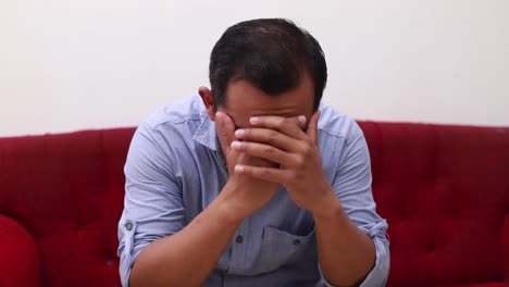 stressed asian man using her mobile phone while sitting on sofa in the living room at home