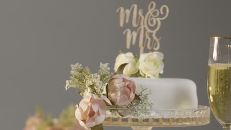 Wedding-Cake-With-Glasses-Of-Champagne-Against-Grey-Studio-Background-At-Wedding-Reception-2