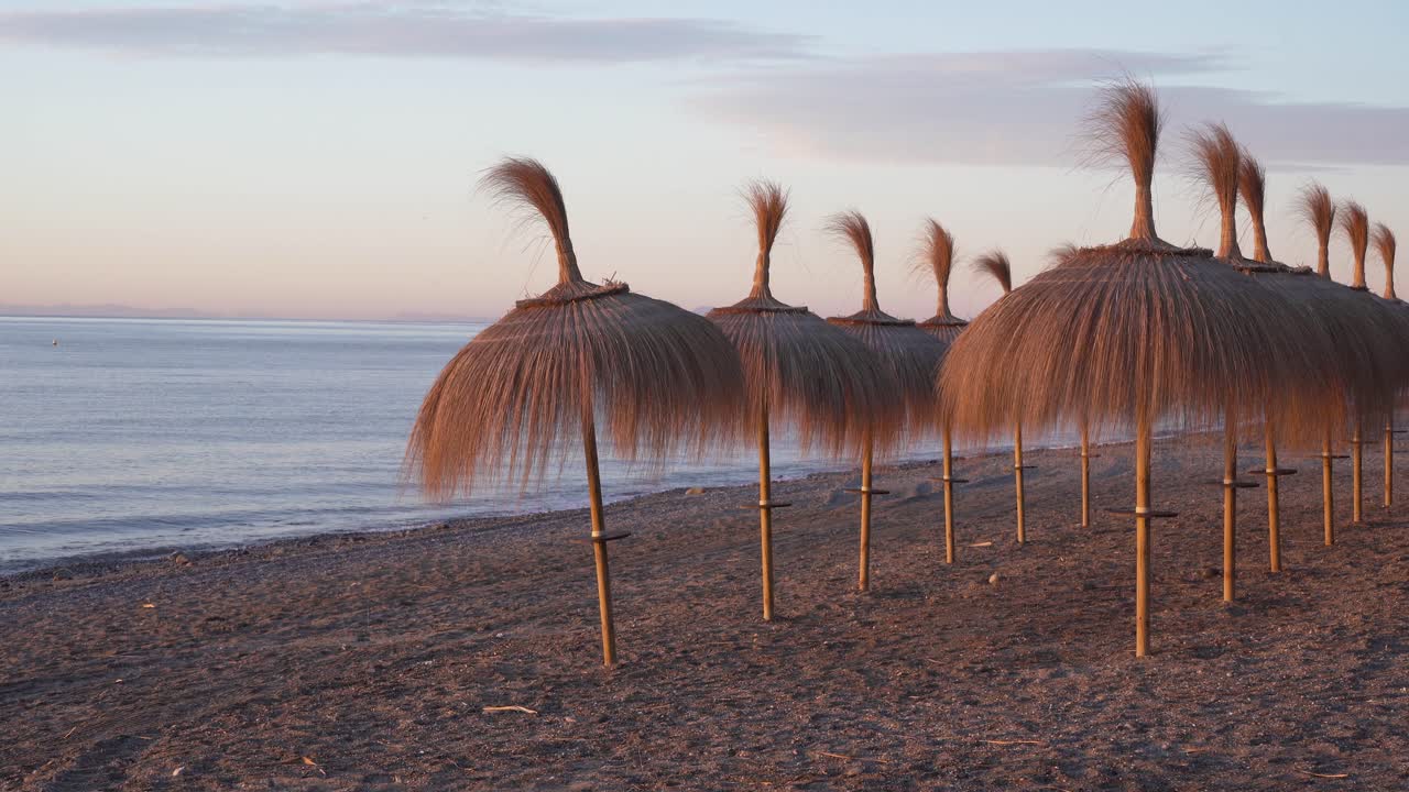 sombrillas tiki en la playa de marbella al amanecer, hermosas imágenes de vacaciones de 4k españa