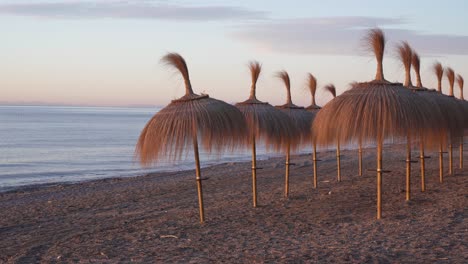 tiki umbrellas on marbella beach at sunrise, beautiful 4k spain holiday footage