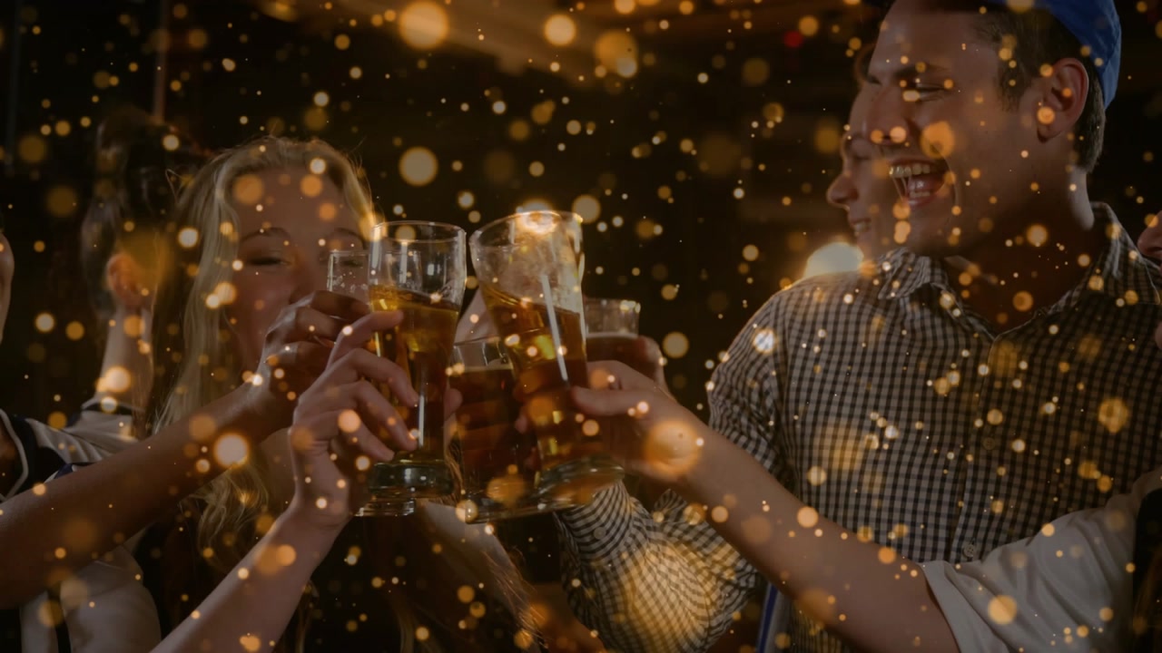 Friends raising pint glasses in bar to center clinking while cheering golden bokeh overlay growing