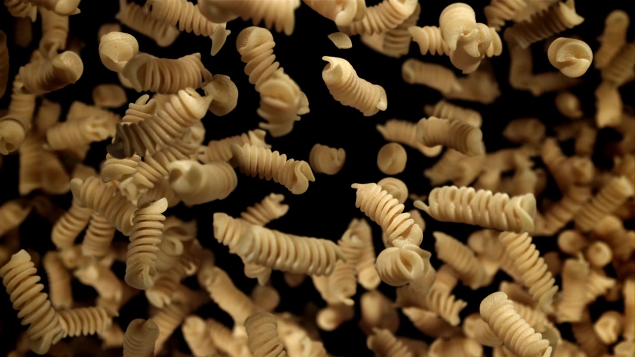 Fusilli secchi che cadono al rallentatore su sfondo nero