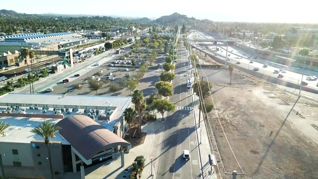 Følger køretøj med drone, mens der panoreres opad, langs en californisk motorvej i downtown Riverside