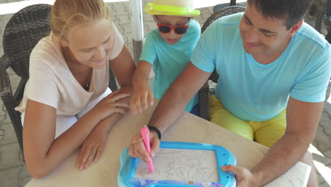 family with magnet board in outdoor cafe