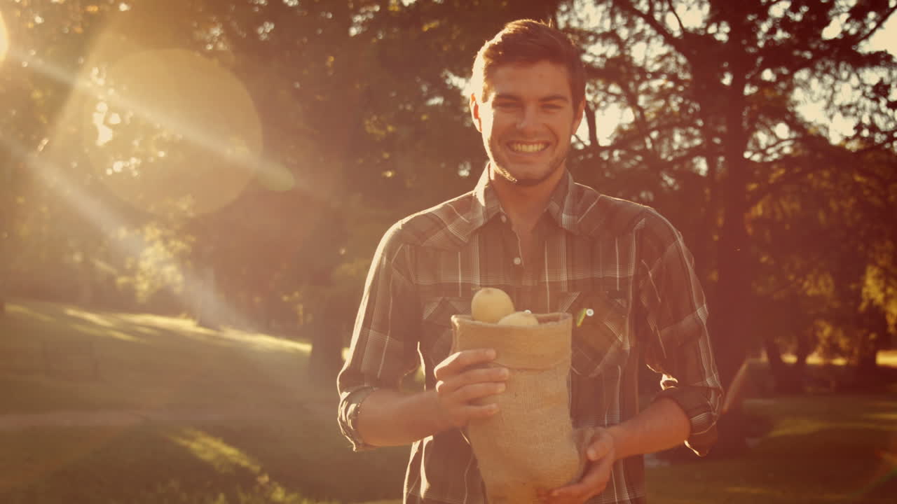 feliz hombre guapo sosteniendo una bolsa con verduras