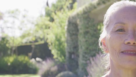 half face portrait of happy senior asian woman smiling in garden, copy space, in slow motion