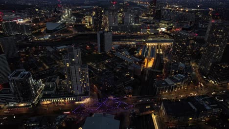 futuristic stratford illuminated night time luxury downtown high rise buildings aerial view dolly left