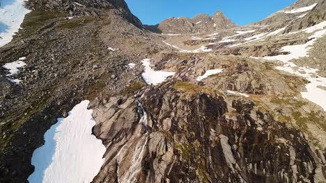 fpv drone footage following a stream made from melting snow up the stunning peaks in northern norway