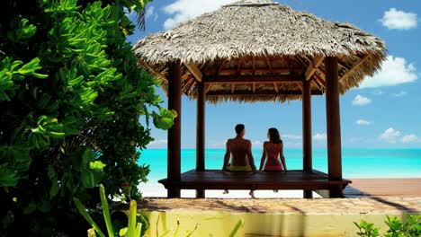 caucasian couple sitting in a caribbean tiki hut