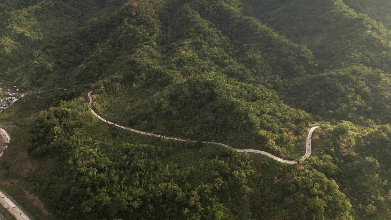 Vista aerea di una strada di montagna tortuosa a Caramoran, Catanduanes, che attraversa lussureggianti colline tropicali e una fitta vegetazione insulare.