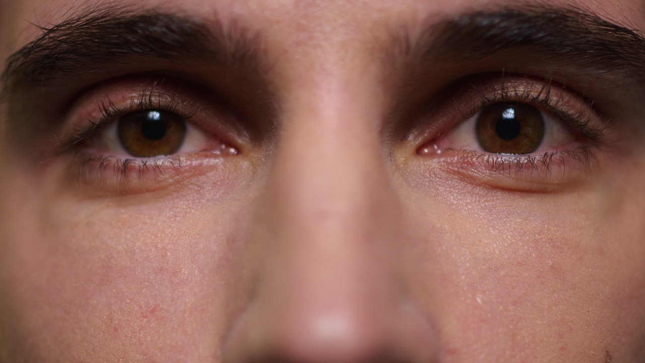 un joven aplaudiendo los ojos. un hombre adulto parpadeando los ojos. un hombre guapo mirando a la cámara.