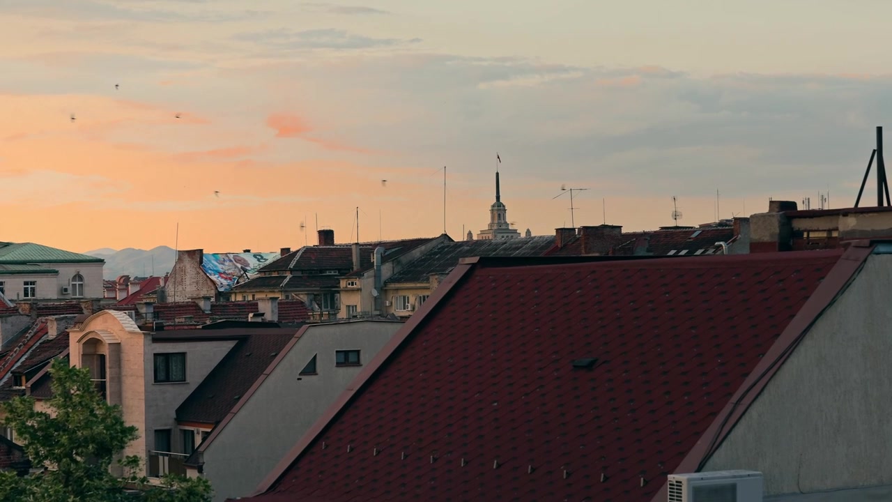 Vue panoramique des toits de Sofia depuis un toit, avec la flèche lointaine du Parlement au coucher du soleil