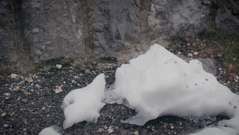 lump of snow melted on grey gravel ground, late winter early spring time