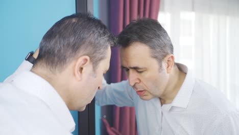 Distressed-man-leans-his-head-on-the-mirror.-Depressed-man.