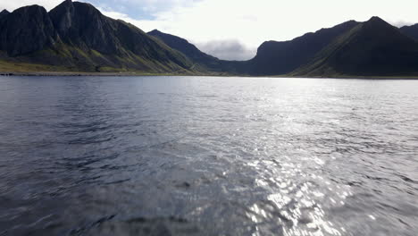 Flying-close-to-the-ocean-in-the-direction-of-the-shore-in-Lofoten,-Norway