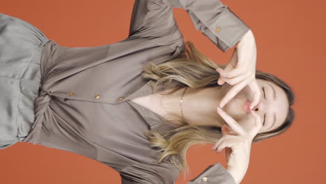 Vertical-video-of-Young-woman-making-heart-sign-at-camera.