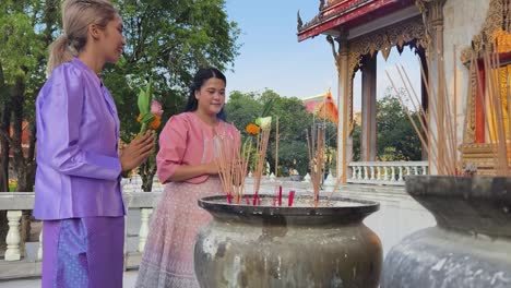 two women praying at a thai temple