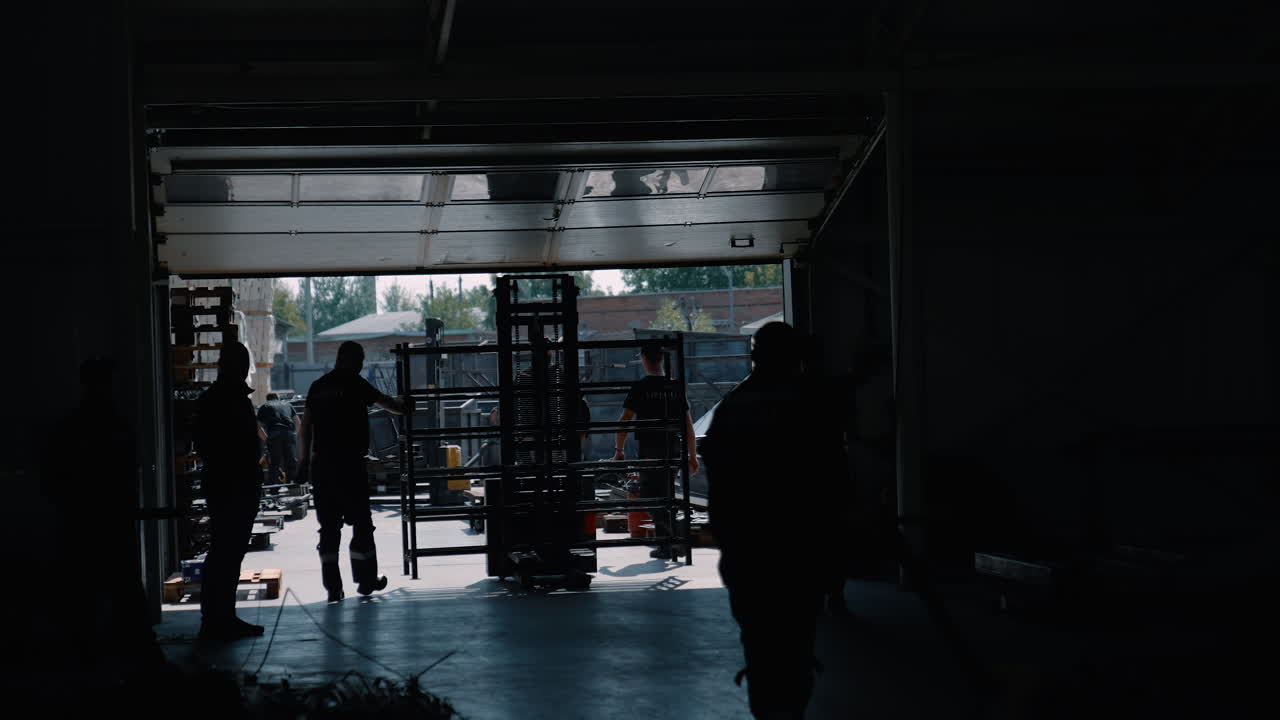 VINNYTSIA, UKRAINE - JANUARY 19, 2023: Workers in overalls walk around a large warehouse. Silhouettes of people