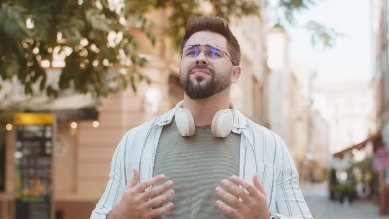 Sad unhappy young man thinks over life concerns suffers from unfair situation on urban city street