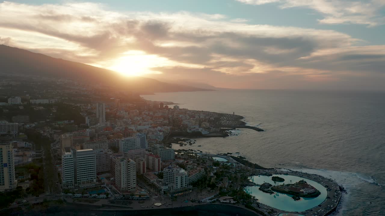 panorama aéreo de los resorts y piscinas de puerto de la cruz rodeados de olas marinas al atardecer, tenerife, islas canarias, españa.