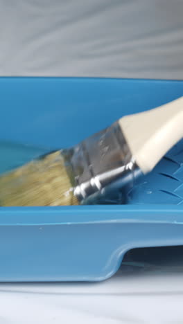 cleaning a paintbrush in a paint tray