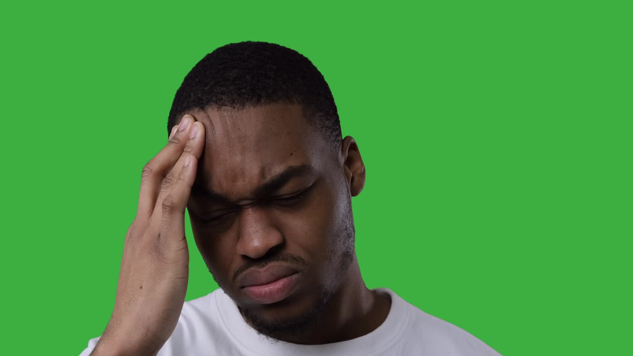Uomo che soffre di forte mal di testa su sfondo verde
