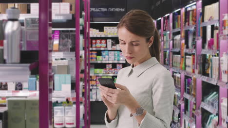 beautiful woman with smartphone in cosmetics store