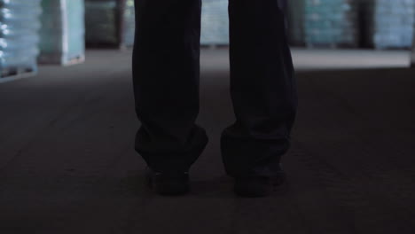 person walking through a dark industrial warehouse